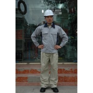 Nam công nhân mặc áo khoác kaki phối màu xám nhạt với cổ và cầu vai xanh than, quần kaki be, đội mũ bảo hộ trắng