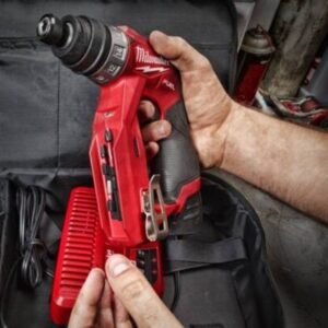 Hai bàn tay thợ đang lắp đầu kẹp mũi khoan vào máy Milwaukee M12 FDDXKIT-0X, nền là túi đồ nghề màu đen