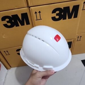 Ảnh thực tế tay cầm mũ bảo hộ 3M H-701SFV-UV trắng có lỗ thoáng, phía sau là các thùng carton in logo 3M