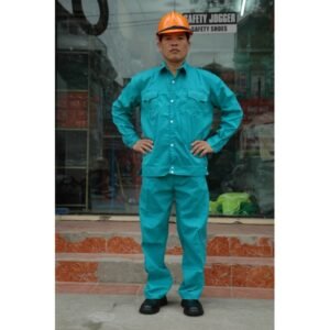 Người mặc bộ quần áo bảo hộ vải kaki màu xanh ngọc, áo dài tay hai túi nắp ngực, đội mũ bảo hộ cam, đi giày bảo hộ đen